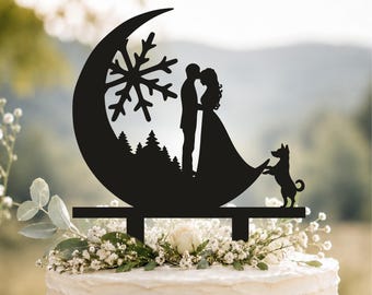 Può includere: Un topper per torta nero a silhouette raffigurante una luna crescente, un grande fiocco di neve, una foresta di pini, una coppia che si fronteggia e un cagnolino in piedi sulle zampe posteriori, con due supporti alla base.