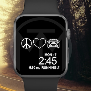 Op de afbeelding: Een zwarte Apple Watch met een witte wijzerplaat waarop de datum, tijd en de tekst "5.50 MI, RUNNING" wordt weergegeven. De wijzerplaat heeft ook een vredesteken, een hart en een auto-icoon. Het horloge is bevestigd aan een zwarte band en is geplaatst tegen een wazige achtergrond van een weg en bomen.