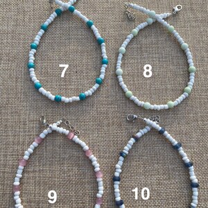 May include: Four beaded necklaces with white beads and different colored accent beads. The necklaces are numbered 7, 8, 9, and 10.