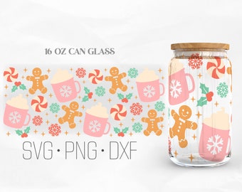 May include: A 16 oz can glass with a winter holiday design. The glass features a repeating pattern of pink mugs with whipped cream and snowflakes, gingerbread people, candy canes, holly leaves, and snowflakes. The text "SVG. PNG. DXF" is at the bottom of the image.