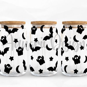 May include: Three clear glass jars with wooden lids, each decorated with a black and white Halloween themed pattern of bats, ghosts, stars, and moons.