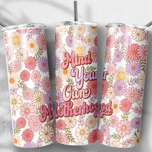 May include: Three stainless steel tumblers with a white background and a floral pattern in shades of pink, purple, and yellow. The middle tumbler has the text "Mind Your Own Motherhood" in pink and orange letters.