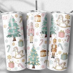 May include: Three white stainless steel tumblers with a Christmas-themed design. The tumblers feature a repeating pattern of Christmas trees, nutcrackers, rocking horses, candy canes, snowflakes, and gift boxes in pink, green, gold, and white.