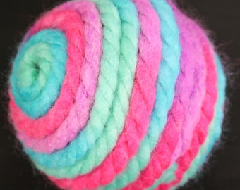 May include: A colorful yarn ball with a spiral pattern in shades of pink, teal, and light green.