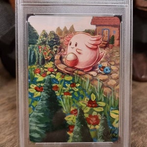 May include: A custom altered Pokemon card featuring Chansey from the Hidden Fates set. The card is graded by CGC and shows Chansey in a pink and white colour scheme, standing on a path in a garden setting. The card is surrounded by a clear plastic case.