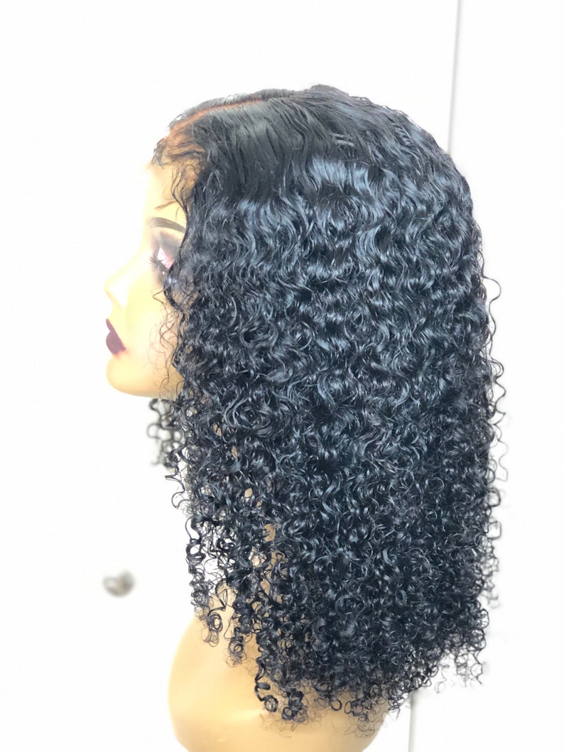 May include: A black, curly wig displayed on a mannequin head. The wig has a natural hairline and is cut to shoulder length. The tightly coiled curls have a glossy finish, giving a voluminous look. The mannequin head is a light skin tone.