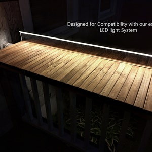 Pode incluir: Uma prateleira de madeira com uma luz LED integrada. A prateleira &eacute; feita de madeira castanha clara e tem uma forma retangular. A luz LED &eacute; uma faixa fina e branca ao longo da borda superior. O texto na imagem diz: "Designed for Compatibility with our exclusive LED light System."