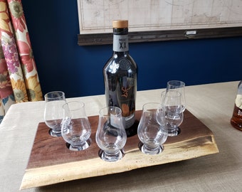 Puede incluir: Una bandeja de servir de madera con cinco vasos pequeños y una botella de whisky "Project XX". La bandeja está hecha de madera oscura con un borde natural y tiene cinco recortes circulares para los vasos.