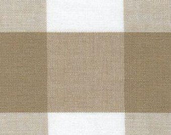 May include: A textile fabric featuring a large-scale buffalo check pattern. The design consists of alternating square blocks of solid light beige and solid white, creating a repeating grid layout with a visible woven texture throughout the material.