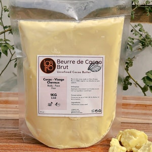 Peut inclure: Un sac en plastique blanc rempli de beurre de cacao brut, étiqueté "Beurre de Cacao Brut" et "Unrefined Cocoa Butter". Le sac comprend également le texte "Corps - Visage - Cheveux" et "Body - Face - Hair". Le sac est posé sur une surface en bois avec quelques morceaux de beurre de cacao à côté.