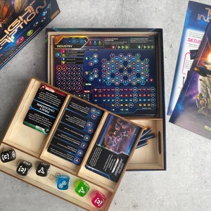 May include: A wooden game organizer with compartments for dice, cards, and tokens. The organizer is designed for the board game "Twilight Inscription".