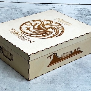 May include: A wooden box with a laser-engraved design featuring a three-headed dragon and the words "Targaryen Fire and Blood". The box also has a laser-engraved image of a castle on the side.