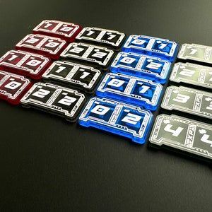 May include: A set of 18 plastic number tiles in red, black, blue, and green. The tiles are numbered 1 through 4 and are arranged in rows.