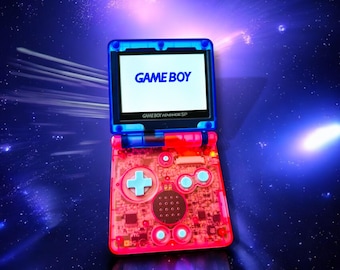 May include: A blue and pink Game Boy Advance SP handheld video game console with the words "GAME BOY" on the screen. The console is against a dark blue background with white stars.