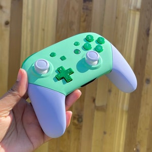 May include: A light green and light blue Nintendo Switch controller with green buttons and white analogue sticks.