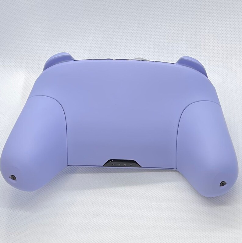 May include: A lavender purple video game controller with a black button panel.
