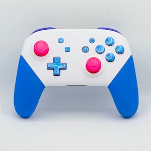 May include: A white and blue Nintendo Switch controller with pink buttons. The controller has a blue and white design with a white faceplate and blue grips.