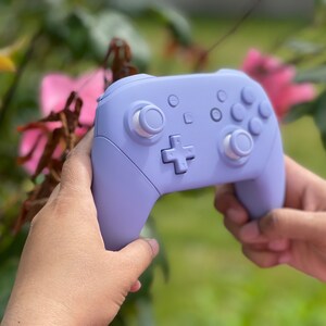 May include: A lavender purple Nintendo Switch controller with white buttons.