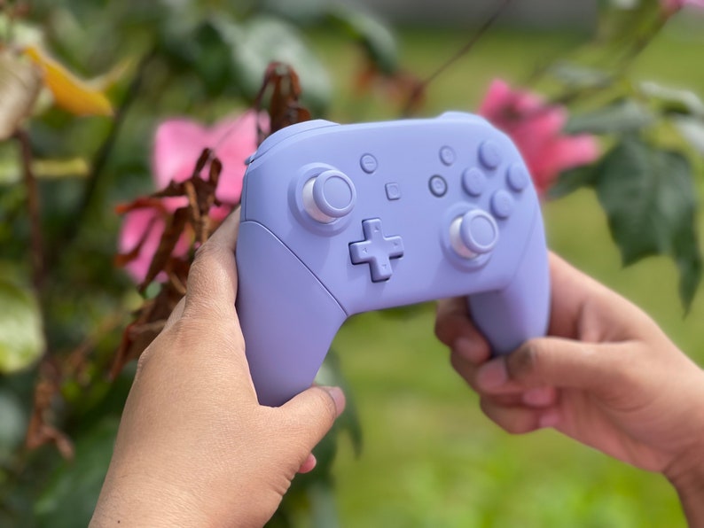 May include: A lavender purple Nintendo Switch controller with white buttons.
