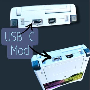 May include: Two white handheld gaming consoles with black accents. The image highlights the USB-C Mod feature, with the text "USB C Mod" overlaid. The consoles have various ports and buttons, including a USB-C port.