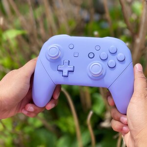 May include: A lavender purple Nintendo Switch controller with white buttons and joysticks.