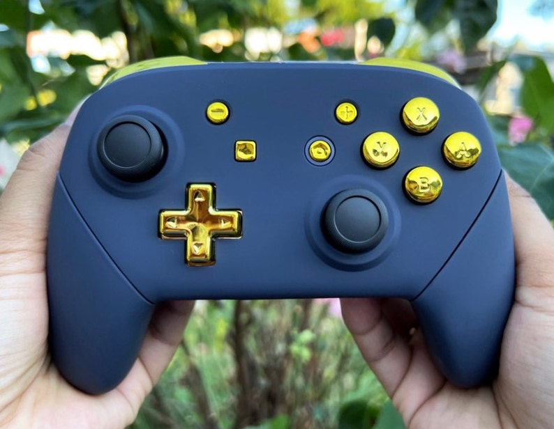 Op de afbeelding: Een donkerblauwe Nintendo Switch-controller met gouden knoppen en een gouden directionele pad.