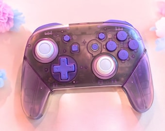 May include: A purple translucent video game controller with white buttons and a purple cross-shaped button. The controller has a clear plastic design, revealing the internal components.