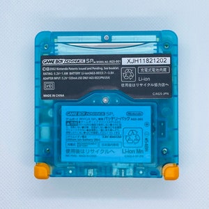 K&ouml;nnte beinhalten: Eine blaue Game Boy Advance SP Handheld-Spielkonsole mit einem schwarz-wei&szlig;en Etikett mit der Aufschrift "GAME BOY ADVANCE SP. MODEL NO. AGS-001 XJH11821202". Das Etikett enth&auml;lt auch Informationen &uuml;ber den Akku, den Adaptereingang und Recyclinghinweise. Die Konsole hat einen gelben Rand um die Kanten.