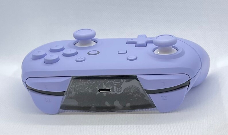 May include: A purple Nintendo Switch controller with white buttons and a USB-C port on the bottom.