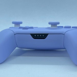 May include: A lavender purple video game controller with white buttons and a black light bar.
