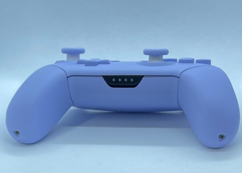 May include: A lavender purple video game controller with white buttons and a black light bar.