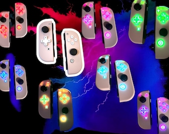 May include: A collection of light-colored game controllers with illuminated buttons in various colors, including red, green, blue, and purple. The controllers are arranged against a dark background with streaks of red, blue, and purple.