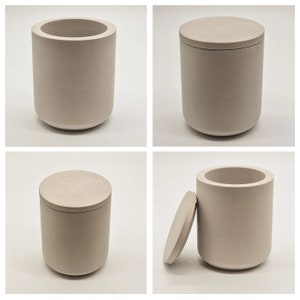 May include: A set of three beige concrete containers with lids. The containers are cylindrical and have a smooth, matte finish.