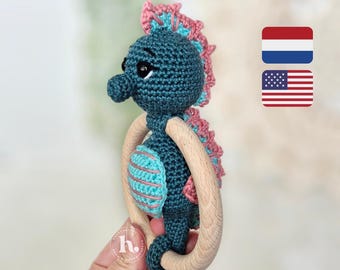 May include: A crocheted seahorse toy with a wooden ring. The seahorse is blue with pink and turquoise stripes. The toy is perfect for a baby or toddler.