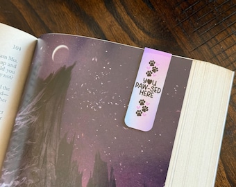 May include: A pink and purple bookmark with paw prints and the text "You Paw-Sed Here".