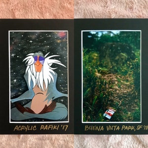 May include: Two framed artworks. The left features a cartoon baboon in a meditative pose against a starry background, labeled "Acrylic Rafiki '17". The right shows a path in a forest, labeled "Buena Vista Park, SF '18".