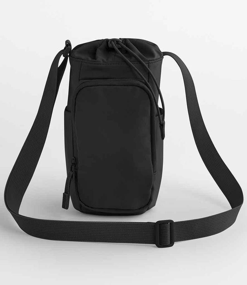 May include: Black water bottle bag with a drawstring closure and a long, adjustable shoulder strap. The bag has a front pocket with a zipper and a side pocket. The bag is made of a durable, water-resistant material.