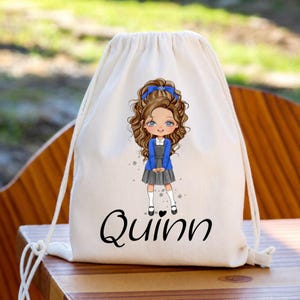 May include: A cream-coloured drawstring backpack featuring a cartoon illustration of a child with long brown hair, a blue bow, a blue cardigan, and a grey skirt. The name Quinn is printed in black cursive script below the illustration.