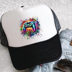 Könnte beinhalten: Schwarze und weiße Trucker-Cap mit einer farbenfrohen Grafik eines Videospiel-Controllers. Der Controller ist in leuchtenden Regenbogenfarben vor einem Farbspritzer dargestellt. Die Kappe hat einen schwarzen Schirm und eine Netzrückseite.