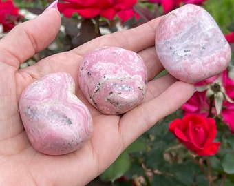May include: Three pink and white tumbled stones with a smooth, polished finish. The stones have a natural, organic shape and are perfect for crystal healing or decoration.