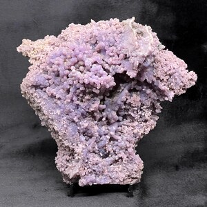 May include: A large, purple agate geode with a rough, textured surface. The geode is filled with small, purple crystals and has a natural, organic shape.