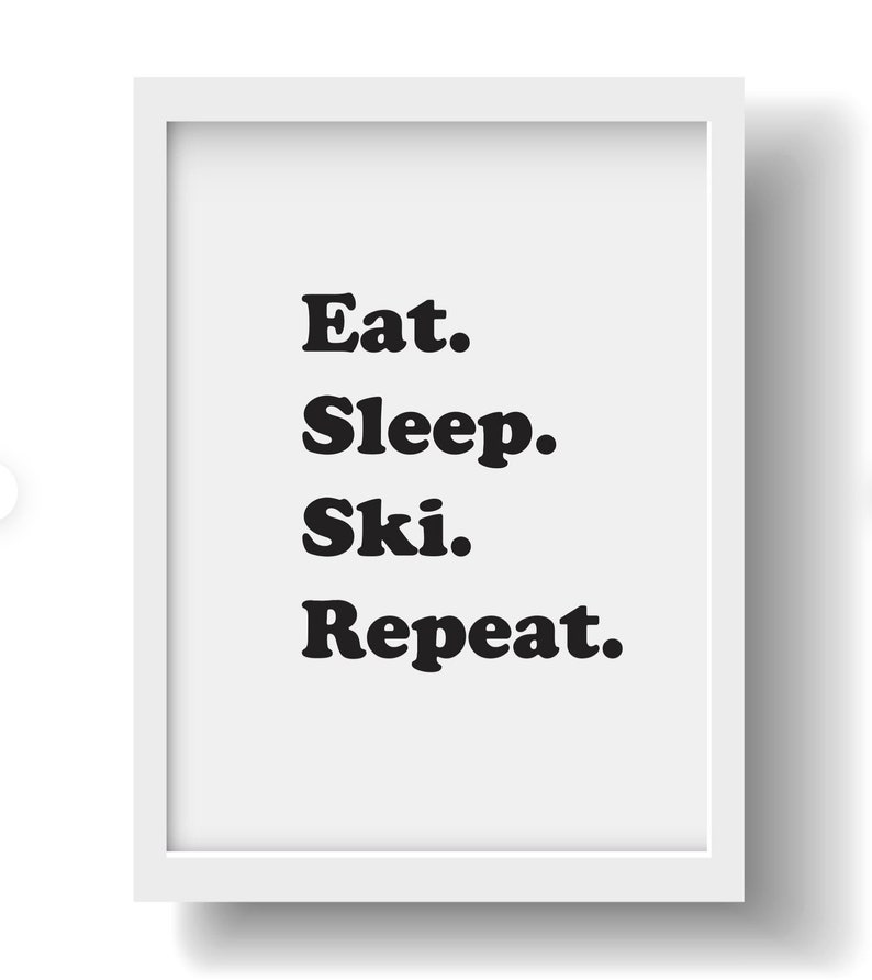 Op de afbeelding: Een wit ingelijst print met zwarte tekst die "Eten. Slapen. Ski&euml;n. Herhalen." luidt.