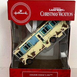 May include: A Hallmark Christmas Vacation ornament featuring Cousin Eddie's RV. The ornament is a detailed replica of the iconic vehicle from the movie, with a white and blue exterior and brown dirt accents. The ornament is packaged in a red box with the National Lampoon's Christmas Vacation logo.