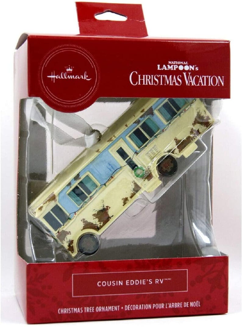 May include: A Hallmark Christmas Vacation ornament featuring Cousin Eddie's RV. The ornament is a detailed replica of the iconic RV from the movie, with a yellow and blue paint scheme and rust detailing. The ornament is packaged in a red box with the National Lampoon's Christmas Vacation logo.
