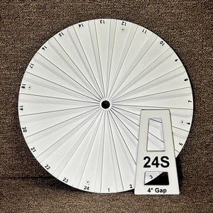 May include: A white circular disc with radial ridges and numbered markings from 1 to 24 around the perimeter. A separate white triangular stand is positioned in front, featuring the text 24S and 4° Gap printed in black on its surface.