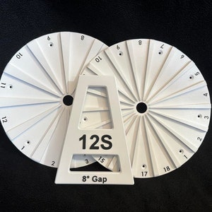 Op de afbeelding: Twee witte ronde gereedschappen met de nummers 1 tot en met 12 en 1 tot en met 18 erop gedrukt. De gereedschappen staan op een witte standaard met de tekst "12S" en "8° Gap".