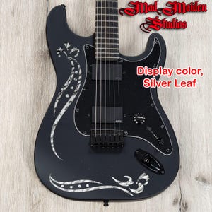 May include: Black electric guitar with silver leaf design. Features a black pickguard, two pickups, and a volume knob. The text "Display color, Silver Leaf" is visible on the guitar.