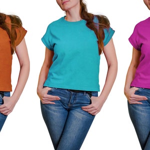 K&ouml;nnte beinhalten: Drei Frauen tragen T-Shirts in verschiedenen Farben. Die Shirts sind orange, t&uuml;rkis und pink. Alle drei Frauen tragen blaue Jeans.