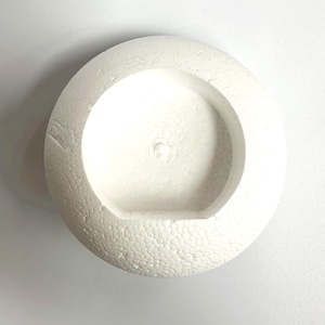 May include: White styrofoam sphere with a round hole in the center. The sphere has a textured surface.