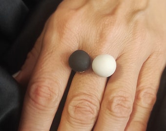 May include: A ring with two round beads, one black and one white.